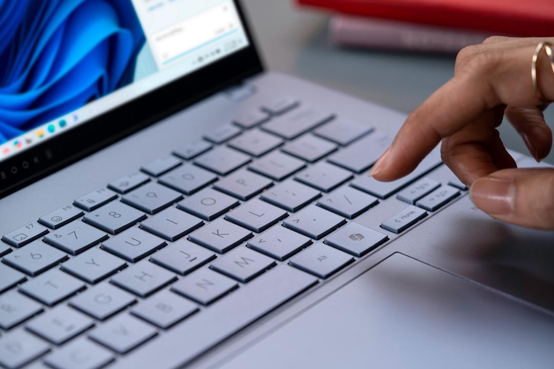 Mão digitando no teclado de um notebook, destacando a importância de aprender atalhos do Windows para aumentar a produtividade.