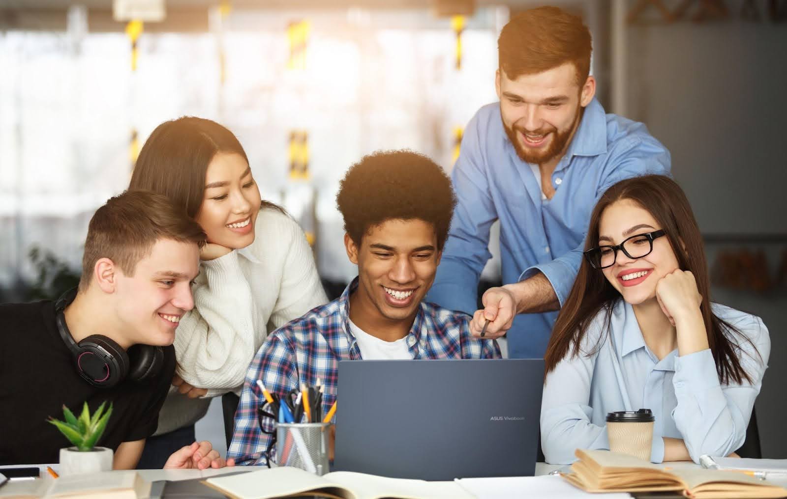 Grupo de jovens estudando ao redor de um notebook, ideal para ilustrar notebook para estudos.