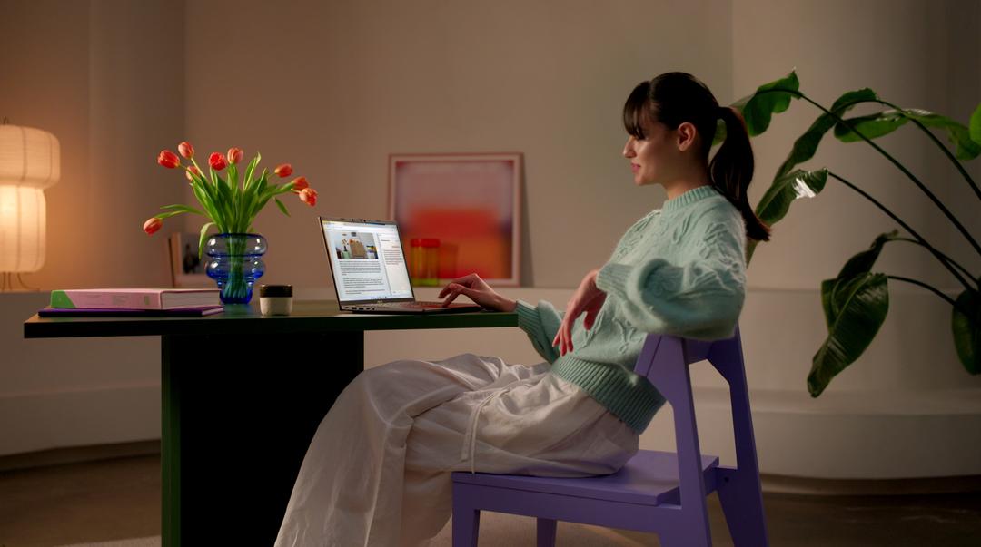 Mulher usando um laptop em uma mesa, em um ambiente moderno e iluminado.
