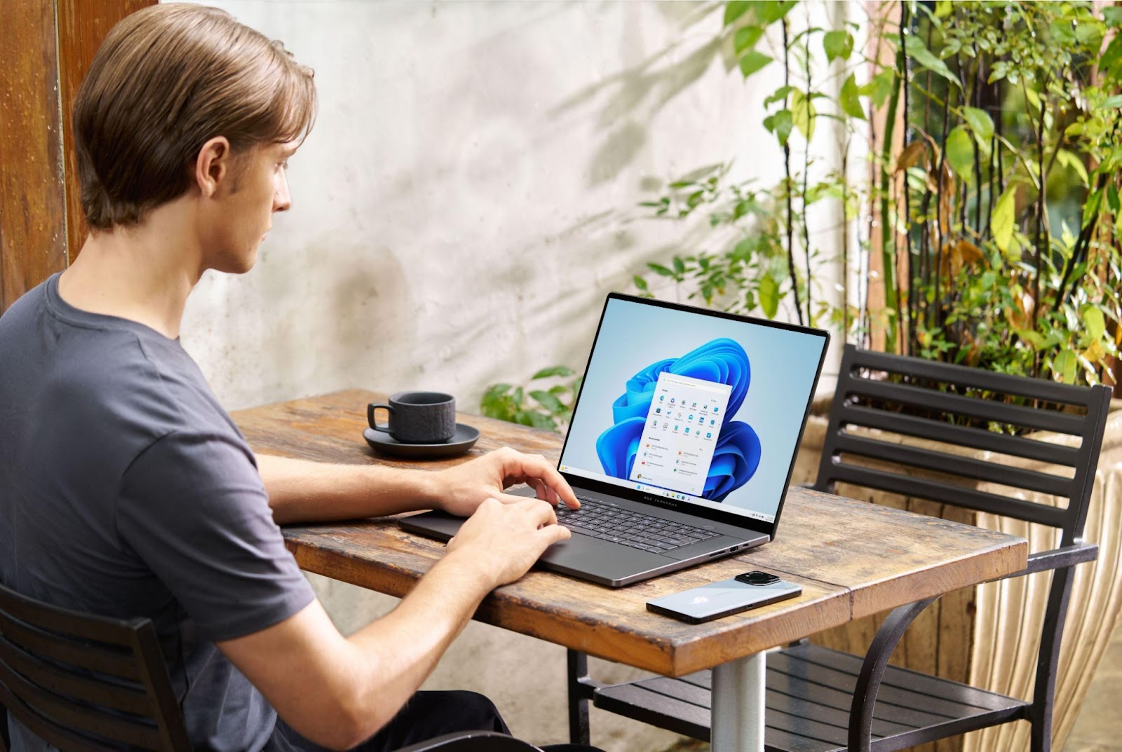 Homem usando o notebook Zephyrus G16 em uma mesa ao ar livre, representando o que é um notebook com ia. 
