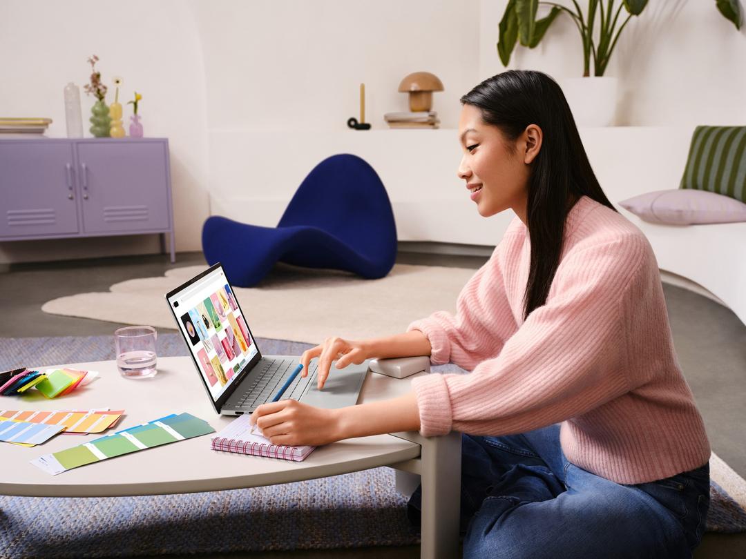 Mulher usando o vivobook s14 em uma mesa, cercada por materiais de estudo, idealizando o melhor notebook para estudar.