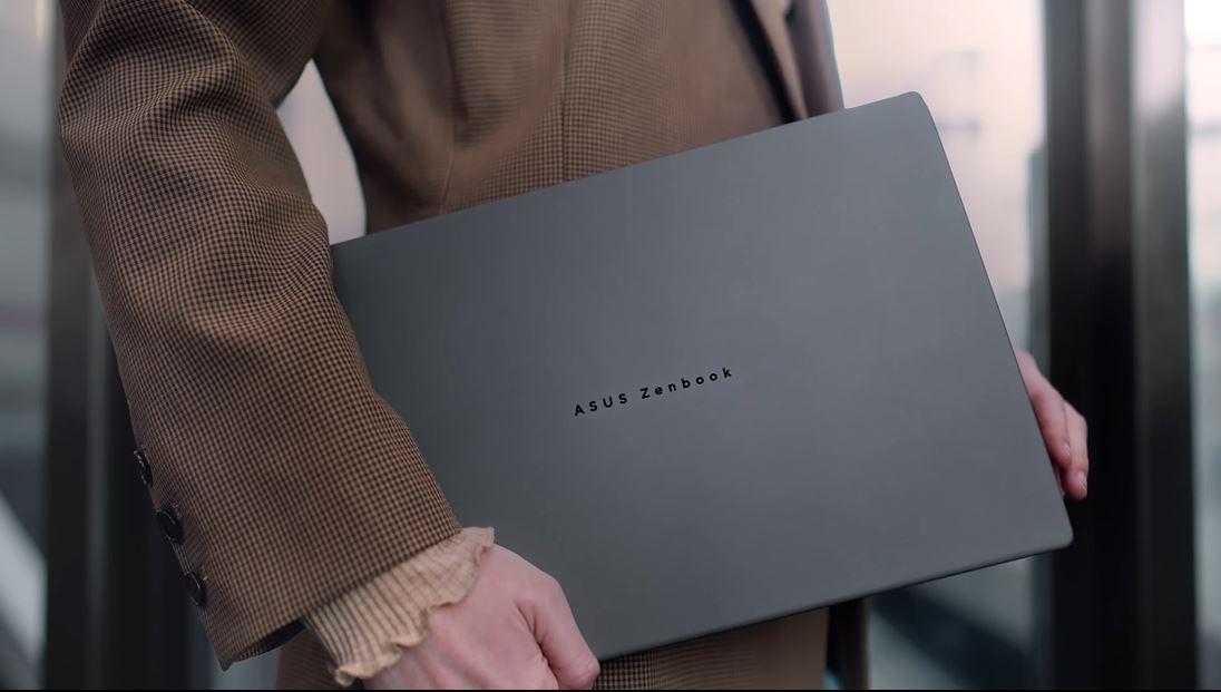 Pessoa segurando um laptop ASUS Zenbook. A imagem foca no dispositivo com o logotipo visível.