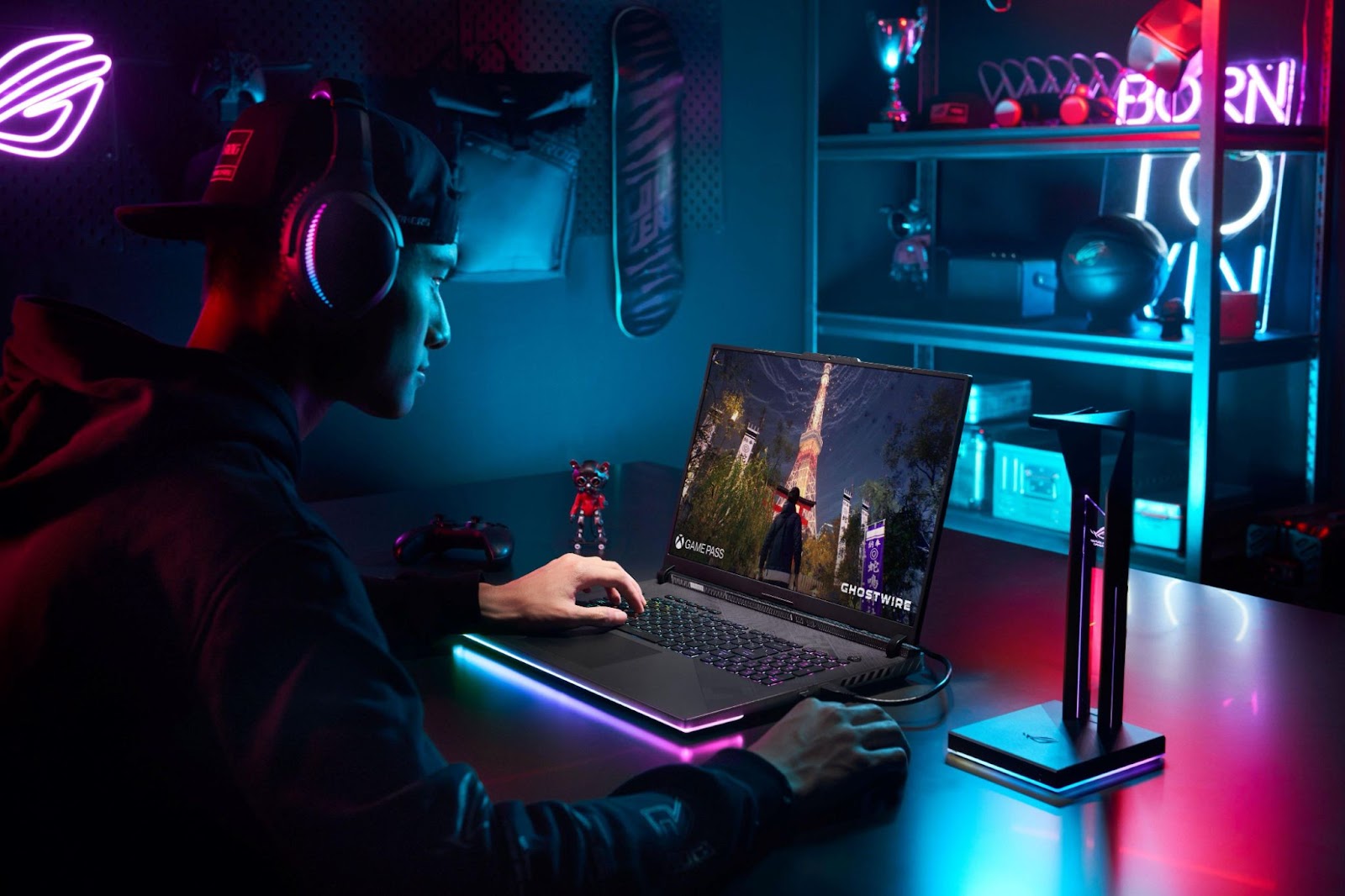 Jovem jogando com um notebook ROG Strix, destacando o melhor notebook gamer, em ambiente com iluminação neon azul e rosa.