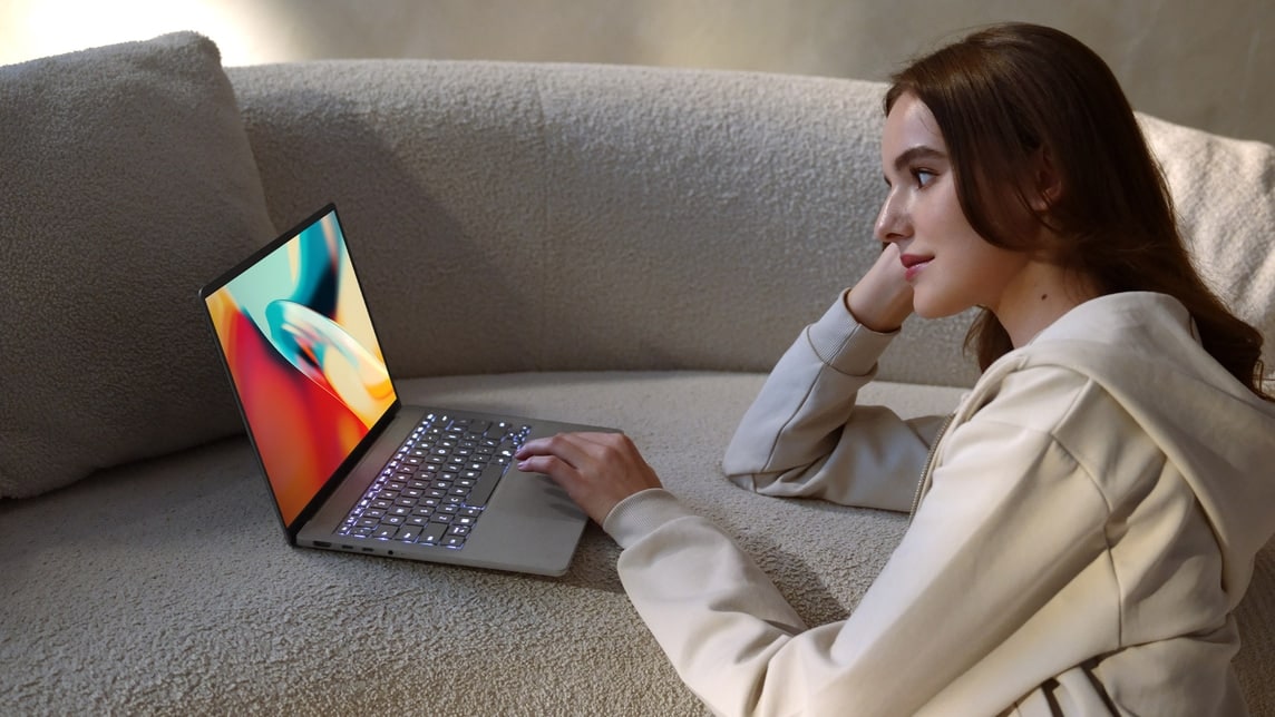 Mulher usando um notebook leve em ambiente confortável, com foco na tela iluminada.