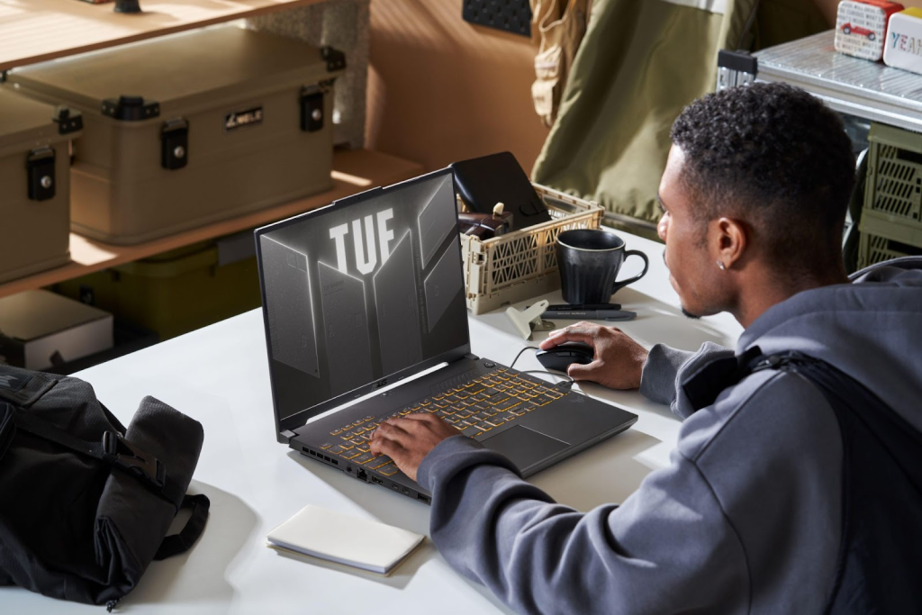 Jovem com um notebook gamer ASUS em uma mesa,destacando a performance do notebook gamer asus.