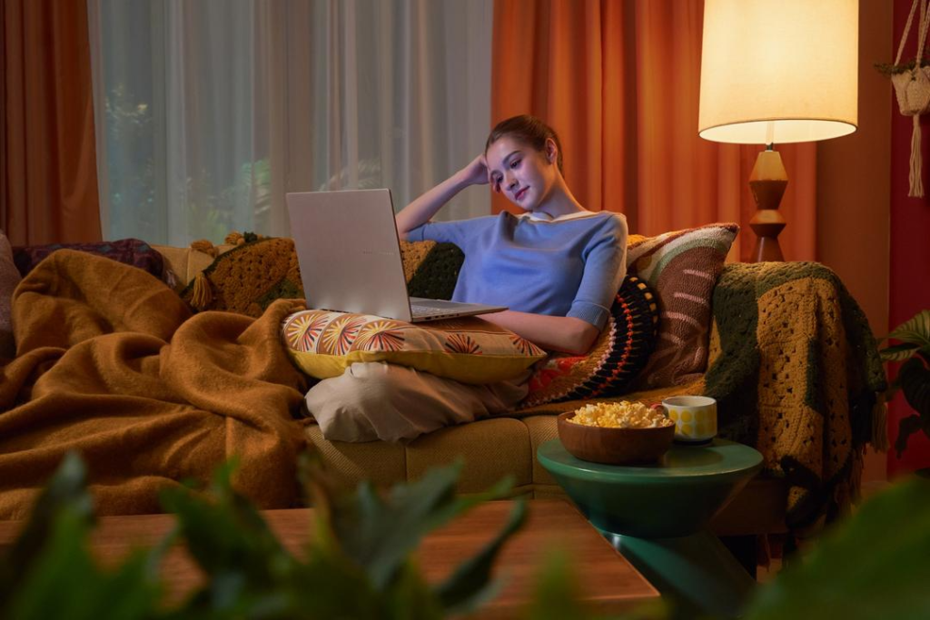 Imagem de uma mulher no sofá de casa, usando um notebook, destacando a experiência de uso do MyASUS em um ambiente doméstico confortável.