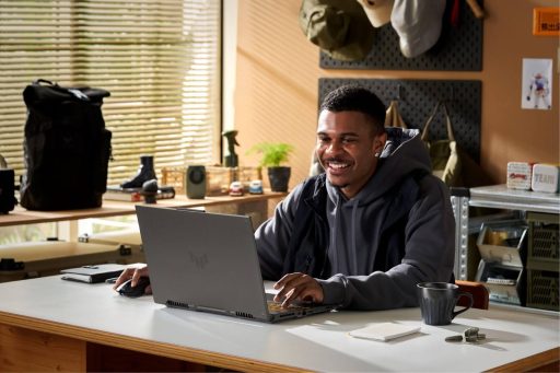 Jovem usando um notebook gamer ASUS em um ambiente de escritório, com iluminação natural.