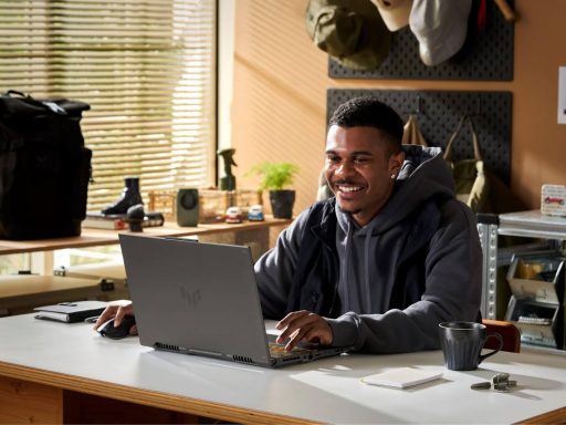 Jovem usando um notebook gamer ASUS em um ambiente de escritório, com iluminação natural.