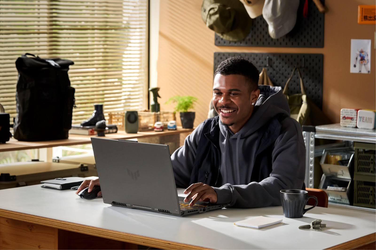 Jovem usando um notebook gamer ASUS em um ambiente de escritório, com iluminação natural.