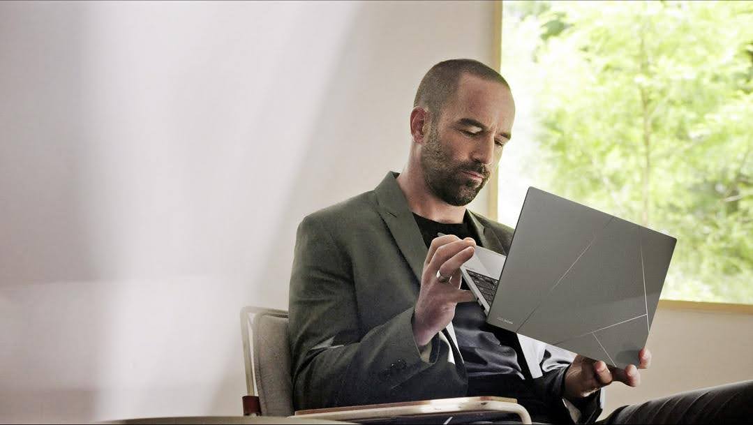 Homem sentado em uma poltrona usando um notebook moderno de acabamento cinza com design geométrico, feito em ceraluminum.