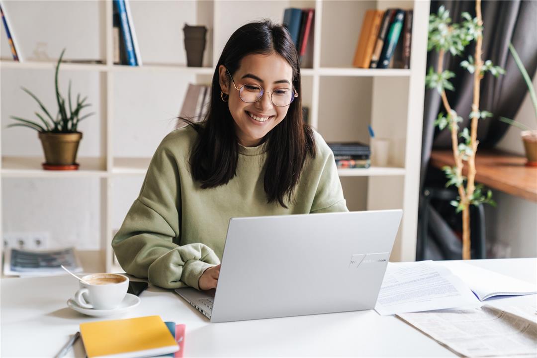 Mulher jovem sorrindo enquanto usa notebook, representando a busca de como saber se um notebook é bom.