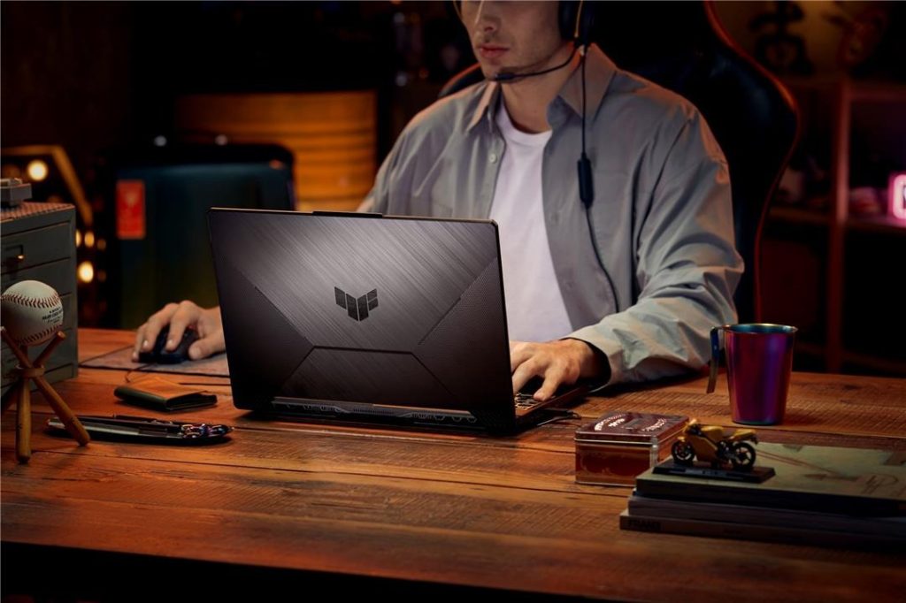 Pessoa utilizando o notebook gamer ASUS TUF Gaming A15 em uma mesa de madeira.