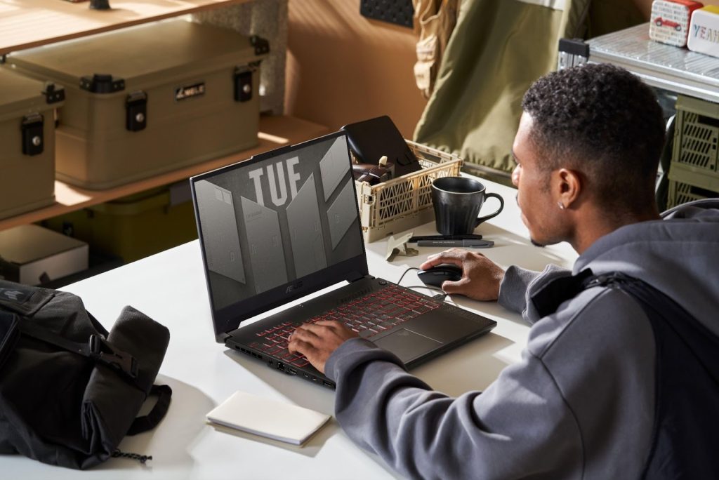 Pessoa usando um notebook ASUS TUF sobre uma mesa organizada, em um ambiente casual, ilustrando o tema black friday asus.