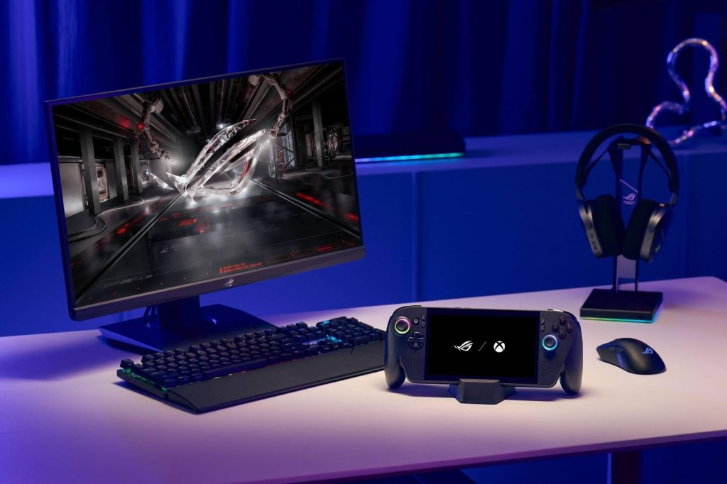 ROG Ally X conectado a um monitor em mesa de jogo, com teclado, mouse e headset ao lado, mostrando o console portátil funcionando como desktop.