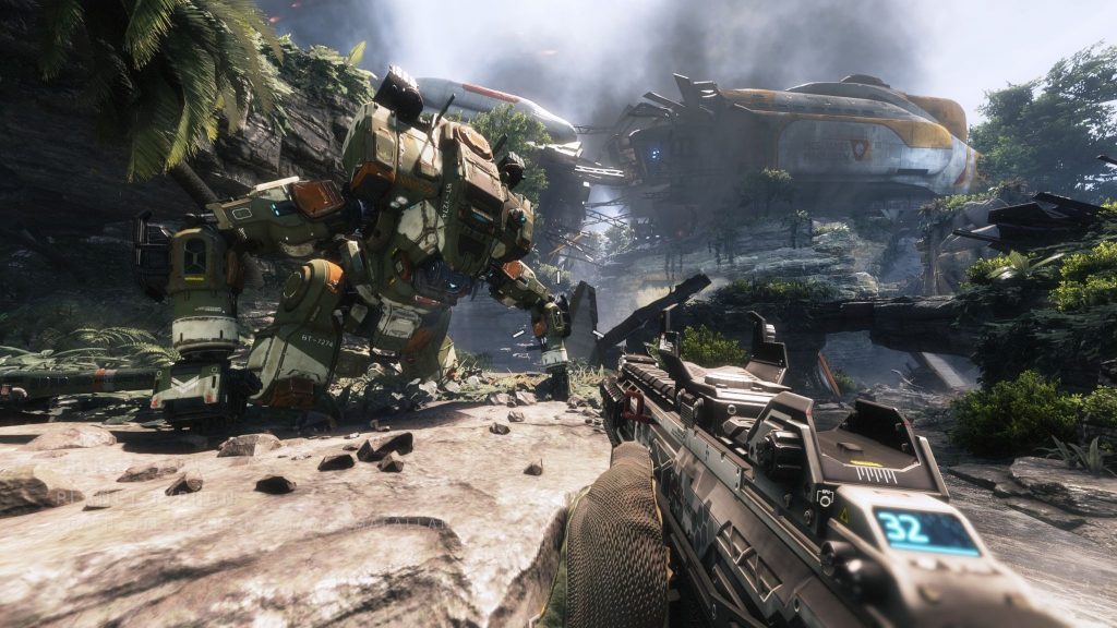 Captura de tela em primeira pessoa de Titanfall 2 mostrando a mira de uma arma tecnológica apontada para um robô gigante Titan em uma selva.